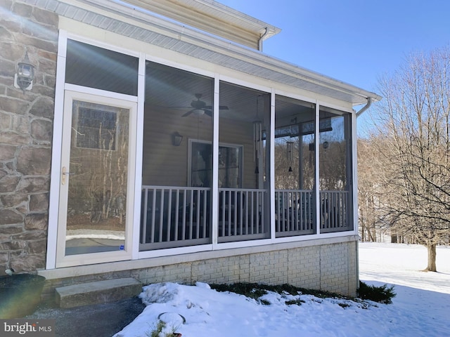 view of snow covered exterior with ceiling fan and a sunroom