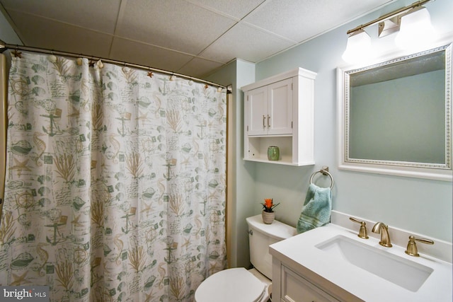 bathroom with curtained shower, a drop ceiling, vanity, and toilet