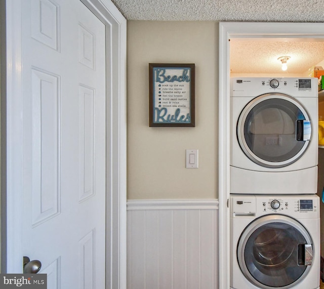 laundry room featuring a textured ceiling and stacked washer and clothes dryer