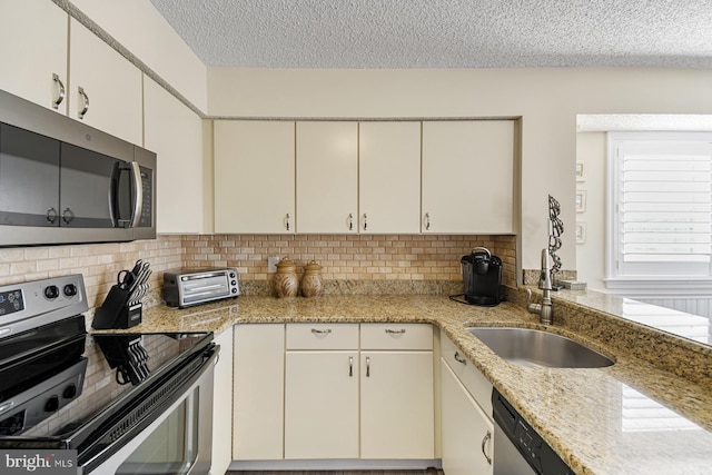 kitchen featuring tasteful backsplash, light stone countertops, a textured ceiling, and appliances with stainless steel finishes