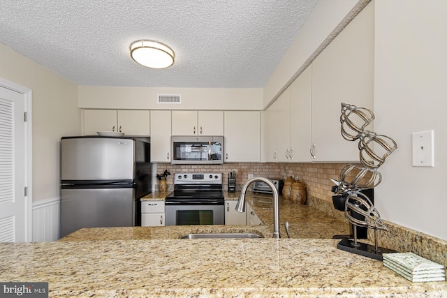 kitchen with white cabinetry, sink, stainless steel appliances, backsplash, and a textured ceiling