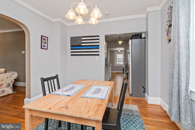 dining area featuring light hardwood / wood-style flooring, ornamental molding, and an inviting chandelier