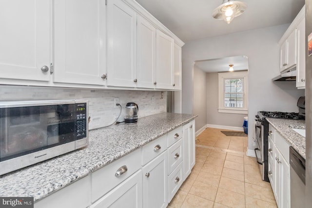 kitchen featuring light stone countertops, white cabinets, appliances with stainless steel finishes, and light tile patterned flooring