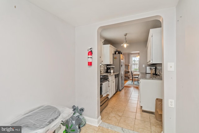 kitchen with light tile patterned floors, backsplash, white cabinetry, and appliances with stainless steel finishes