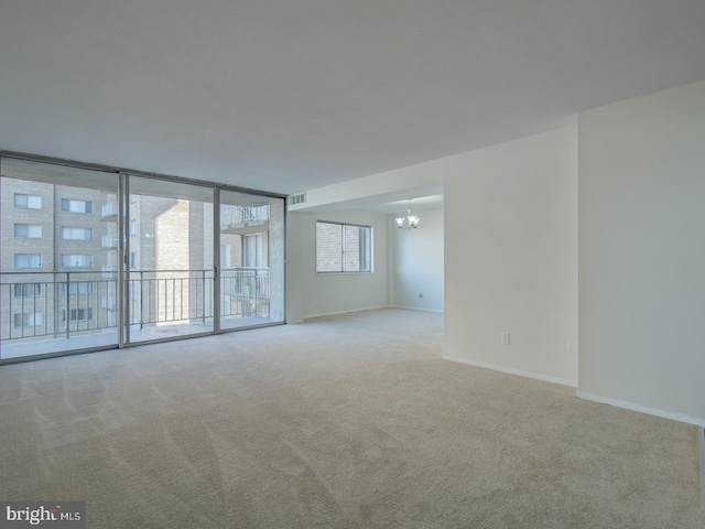 carpeted spare room featuring a notable chandelier and expansive windows