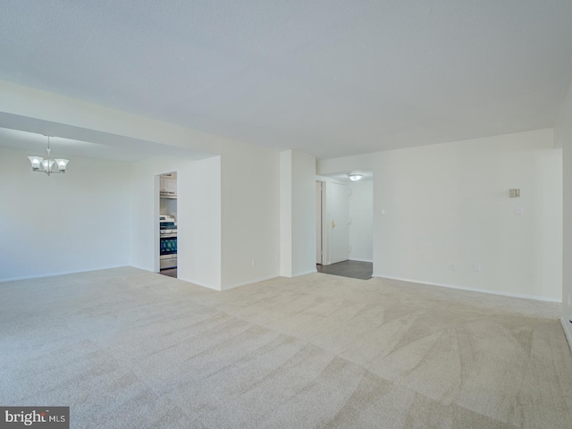 unfurnished room with a notable chandelier and light colored carpet