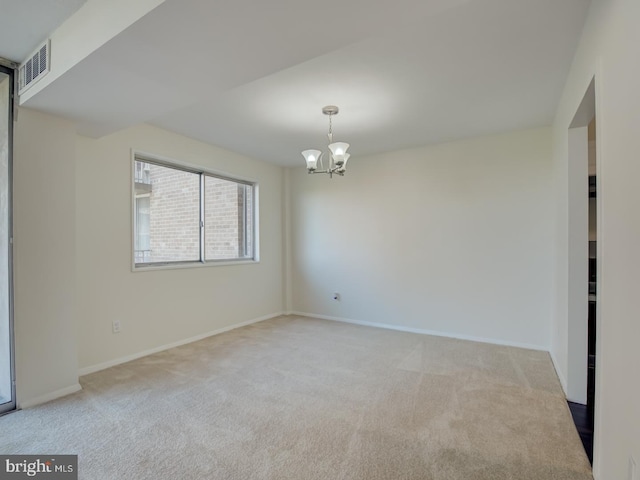 spare room with light carpet and a chandelier