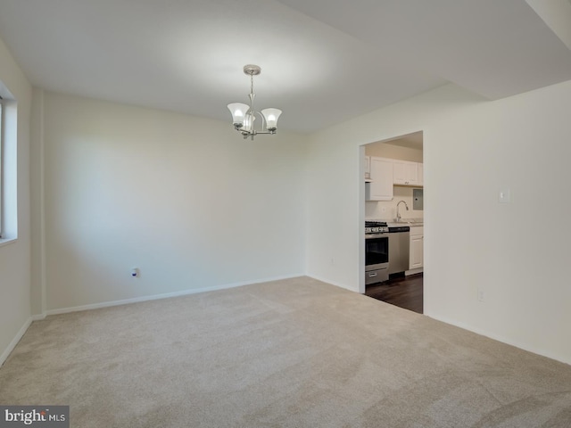 spare room featuring a chandelier, dark colored carpet, and sink