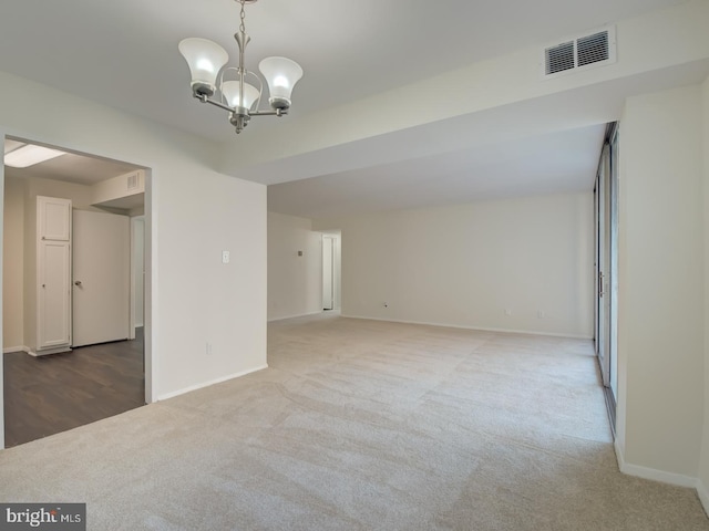 empty room with carpet floors and a notable chandelier