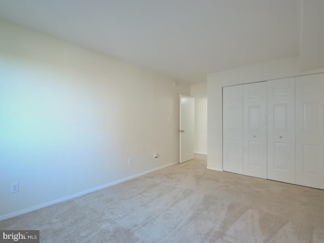 unfurnished bedroom with light carpet and a closet