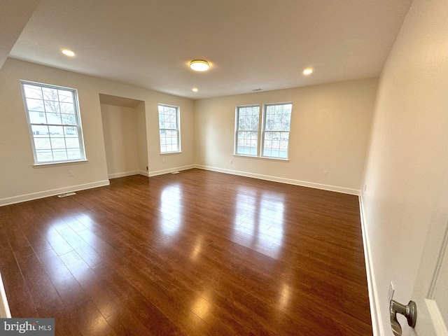 empty room with a healthy amount of sunlight and dark hardwood / wood-style flooring