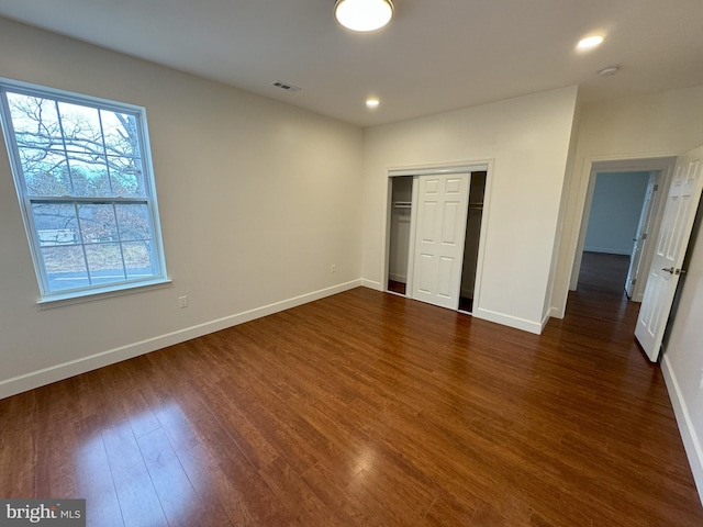 unfurnished bedroom featuring dark wood-type flooring and a closet