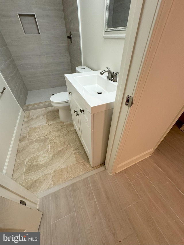 bathroom featuring vanity, tiled shower, and toilet