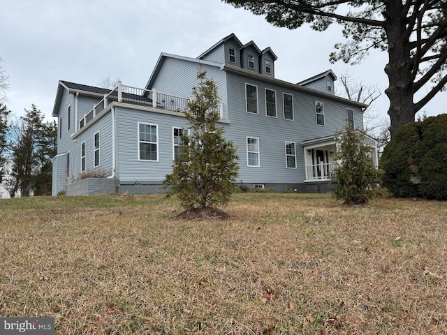 back of property with a balcony and a yard