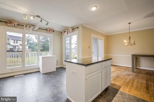 kitchen with lofted ceiling, white cabinets, hanging light fixtures, a center island, and an inviting chandelier