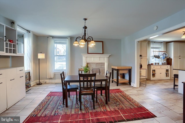 dining space with a notable chandelier, a fireplace, and baseboards