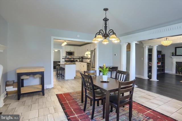 dining room with baseboards, a high end fireplace, and ornate columns