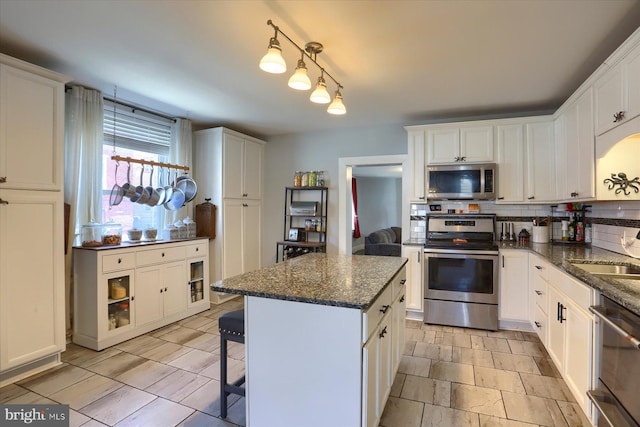 kitchen with backsplash, white cabinetry, stainless steel appliances, and a sink