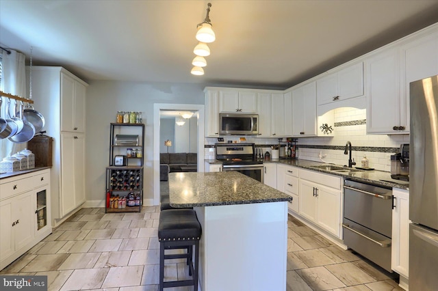 kitchen with tasteful backsplash, a center island, appliances with stainless steel finishes, white cabinets, and a sink