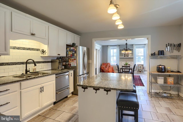 kitchen featuring a sink, a center island, white cabinetry, a breakfast bar area, and decorative backsplash