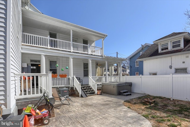 exterior space featuring a balcony, fence, a hot tub, central air condition unit, and a patio area