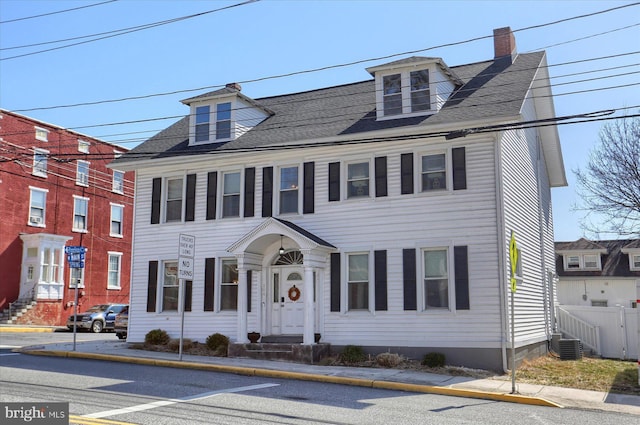 view of front of home featuring entry steps, a chimney, and fence