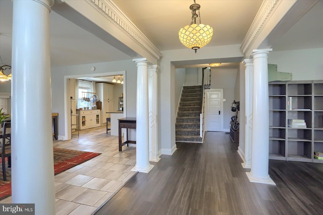 entryway with wood finished floors, stairs, baseboards, and decorative columns