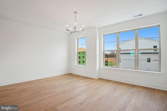 empty room with light wood-type flooring and a chandelier