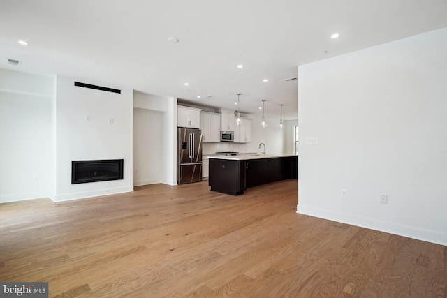 unfurnished living room with sink and light hardwood / wood-style floors