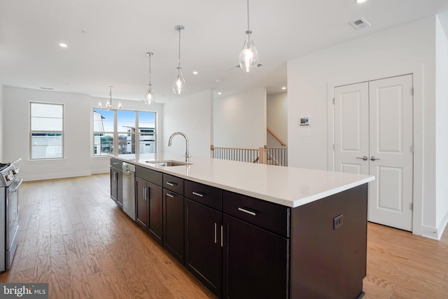 kitchen featuring an island with sink, light wood-type flooring, sink, and pendant lighting