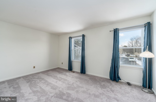 unfurnished room with light carpet, visible vents, and baseboards