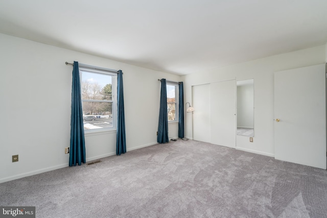 spare room with light colored carpet, visible vents, and baseboards