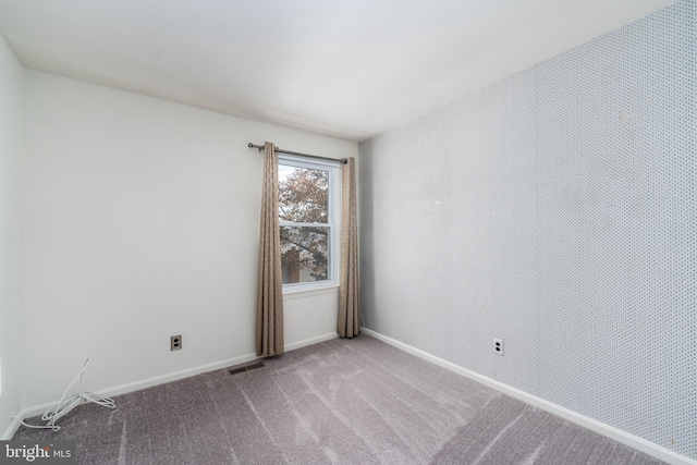 carpeted spare room with visible vents and baseboards