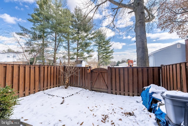 yard covered in snow with a gate and fence