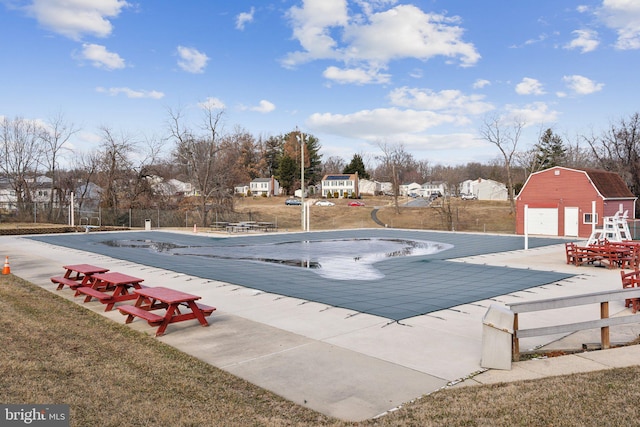 pool featuring a barn, a patio, an outdoor structure, and a lawn