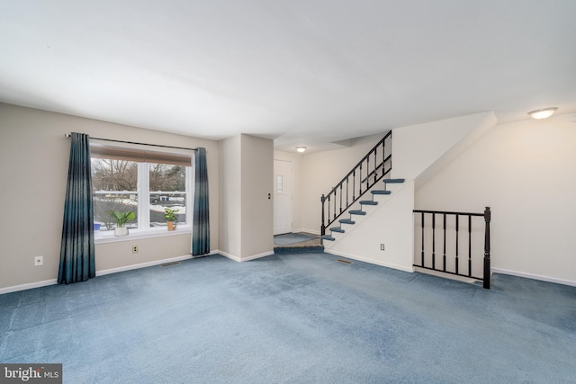 carpeted spare room with stairs, visible vents, and baseboards