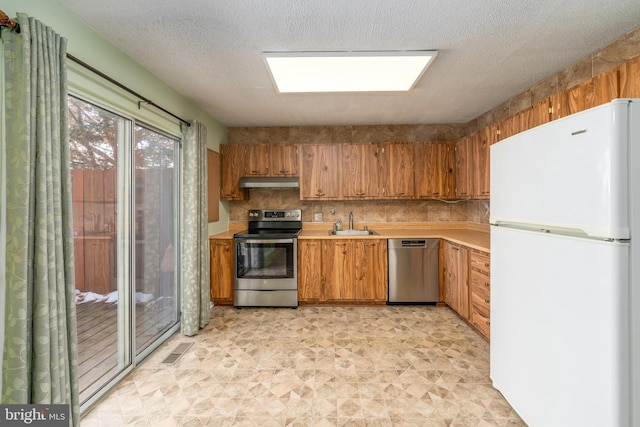 kitchen with light countertops, appliances with stainless steel finishes, visible vents, and under cabinet range hood