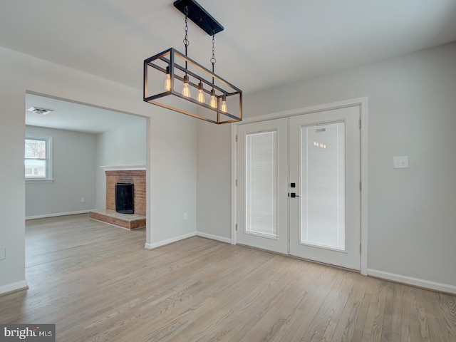 interior space featuring a fireplace, light wood-type flooring, and french doors