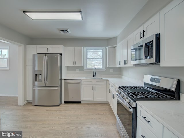 kitchen featuring white cabinets, stainless steel appliances, a wealth of natural light, and sink