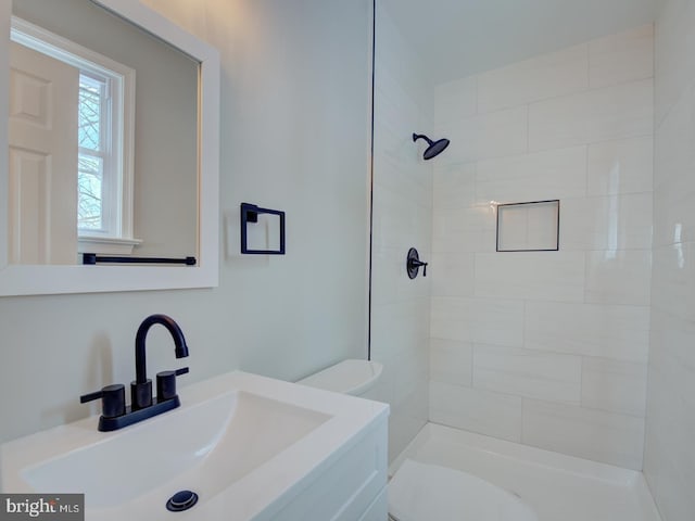 bathroom featuring toilet, a tile shower, and vanity