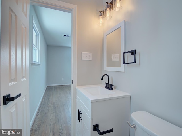 bathroom featuring wood-type flooring, vanity, and toilet