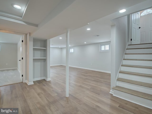 basement featuring light wood-type flooring and built in features