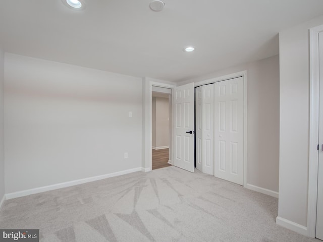 unfurnished bedroom featuring light colored carpet and a closet