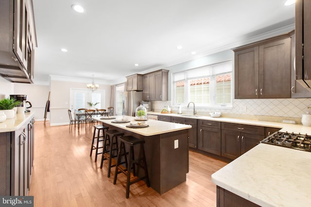 kitchen featuring a kitchen island, a breakfast bar, a chandelier, light hardwood / wood-style floors, and stainless steel refrigerator with ice dispenser