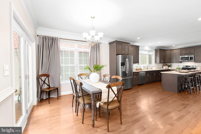 dining area with crown molding, light hardwood / wood-style flooring, and a chandelier