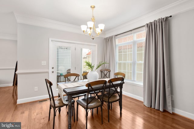 dining area with crown molding, plenty of natural light, a chandelier, and hardwood / wood-style flooring