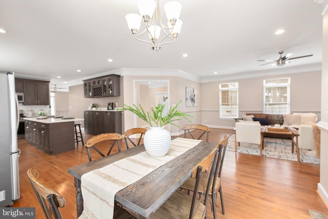 dining room with crown molding, ceiling fan with notable chandelier, and light wood-type flooring