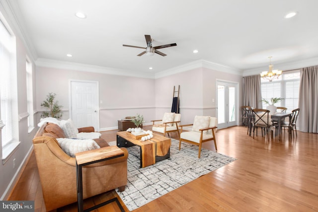 living room featuring crown molding, plenty of natural light, and ceiling fan with notable chandelier