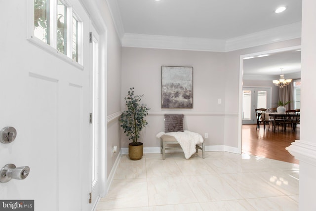 foyer with crown molding, plenty of natural light, and a notable chandelier