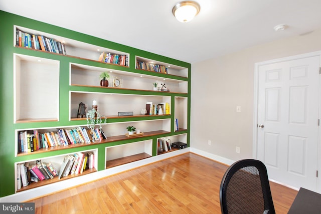 office space with built in shelves and wood-type flooring